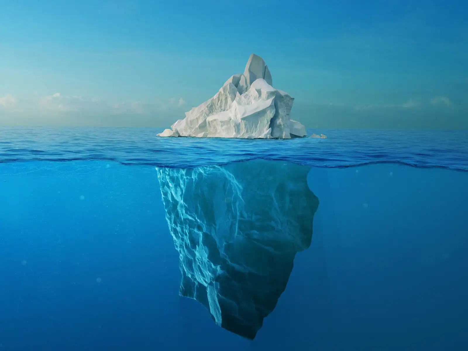 Picture of an iceberg at the surface having a massive base under the water. This suggests the high underlying costs when it comes to healthcare.