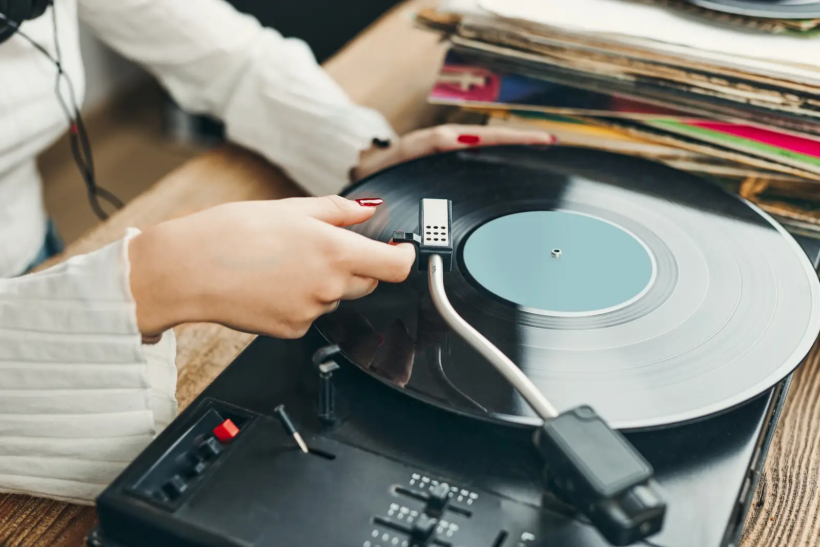 Picture of a woman putting the needle of the turntable on the vinyl record, likely an audiophile