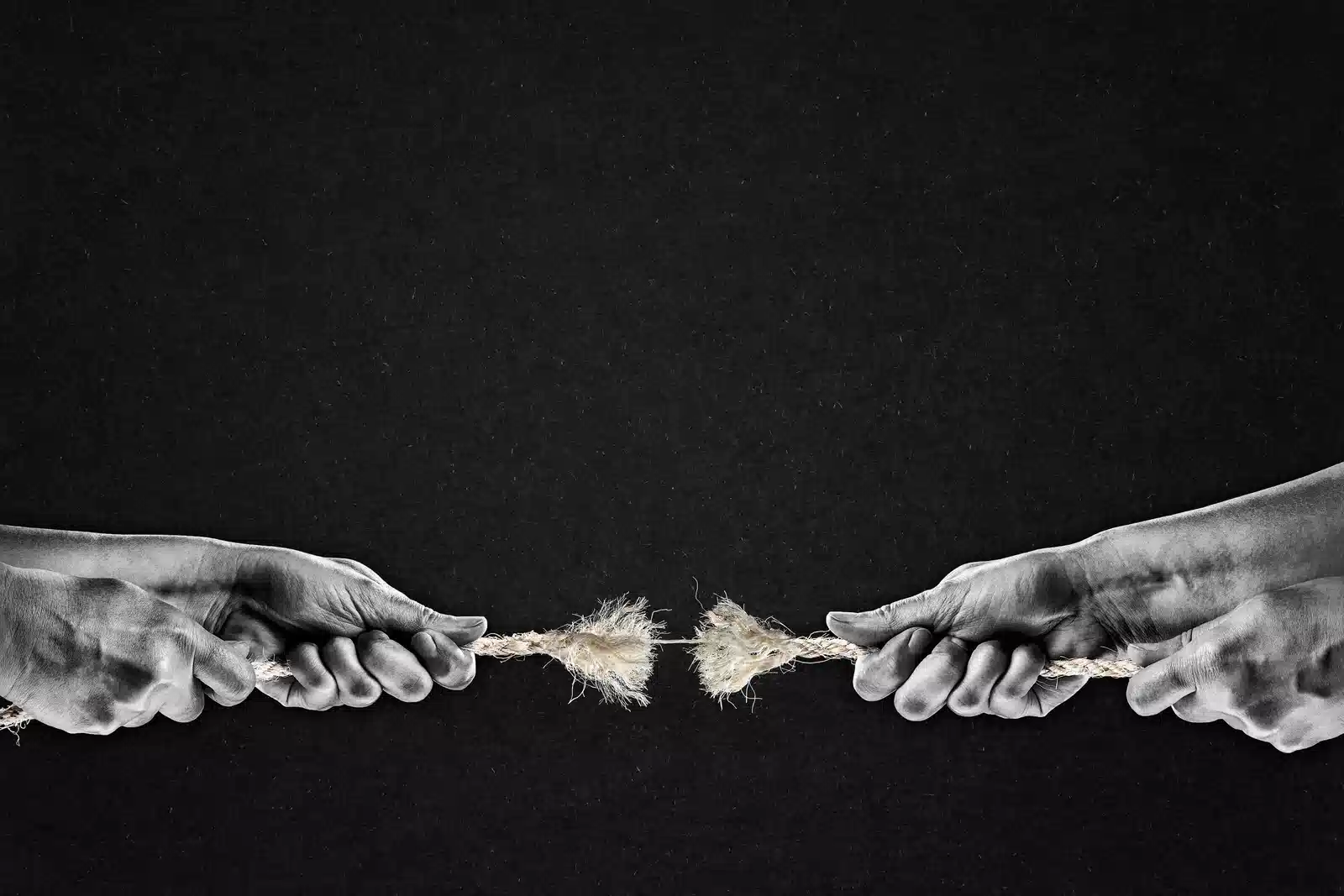 picture of two hands pulling a rope hanging by a thread and being ready to break.