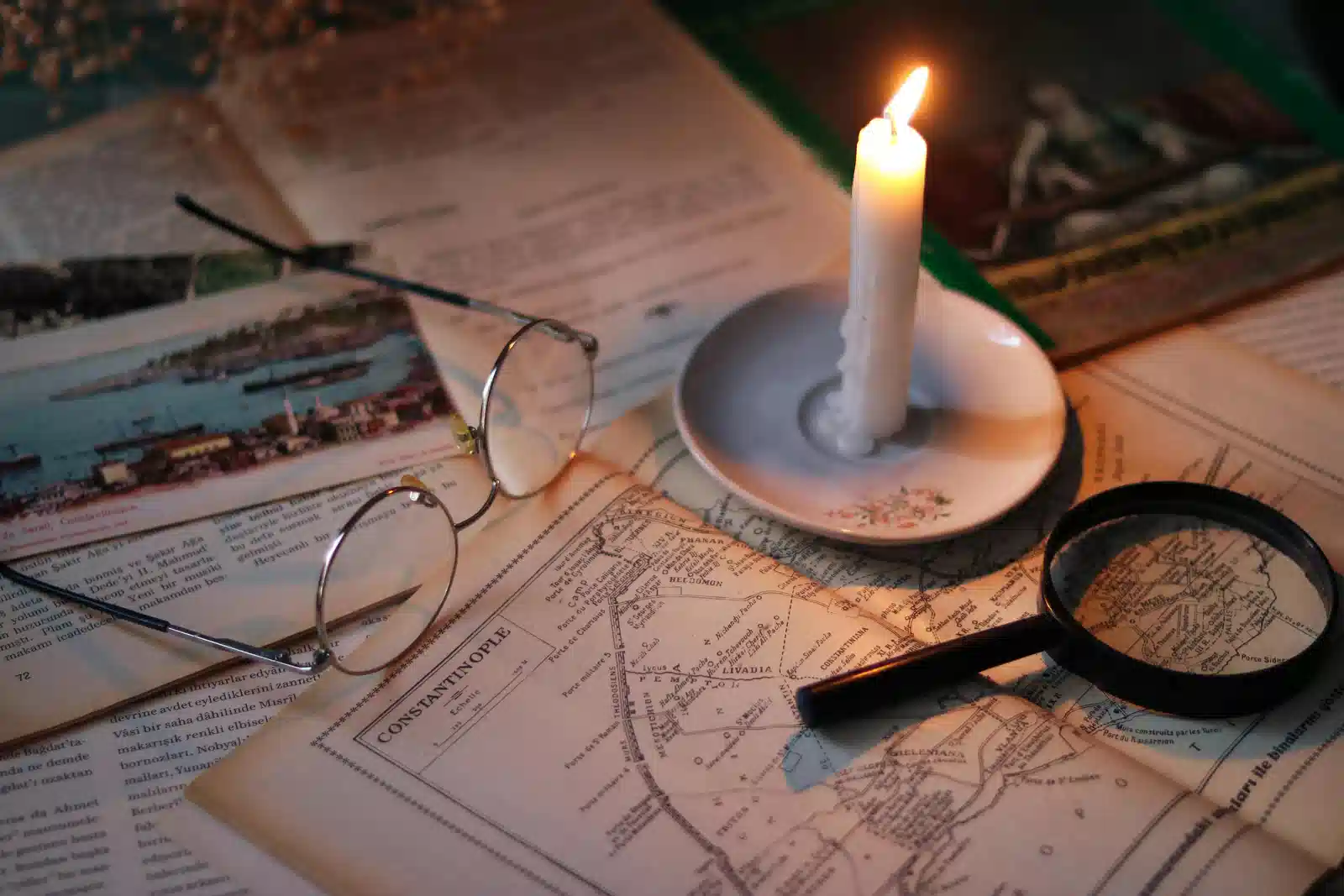 Picture of an old map, on a desk in a moody lighting provided by a candle. This picture suggests the research for the hunt, the hyperfocus highlighted in the blog content.. 