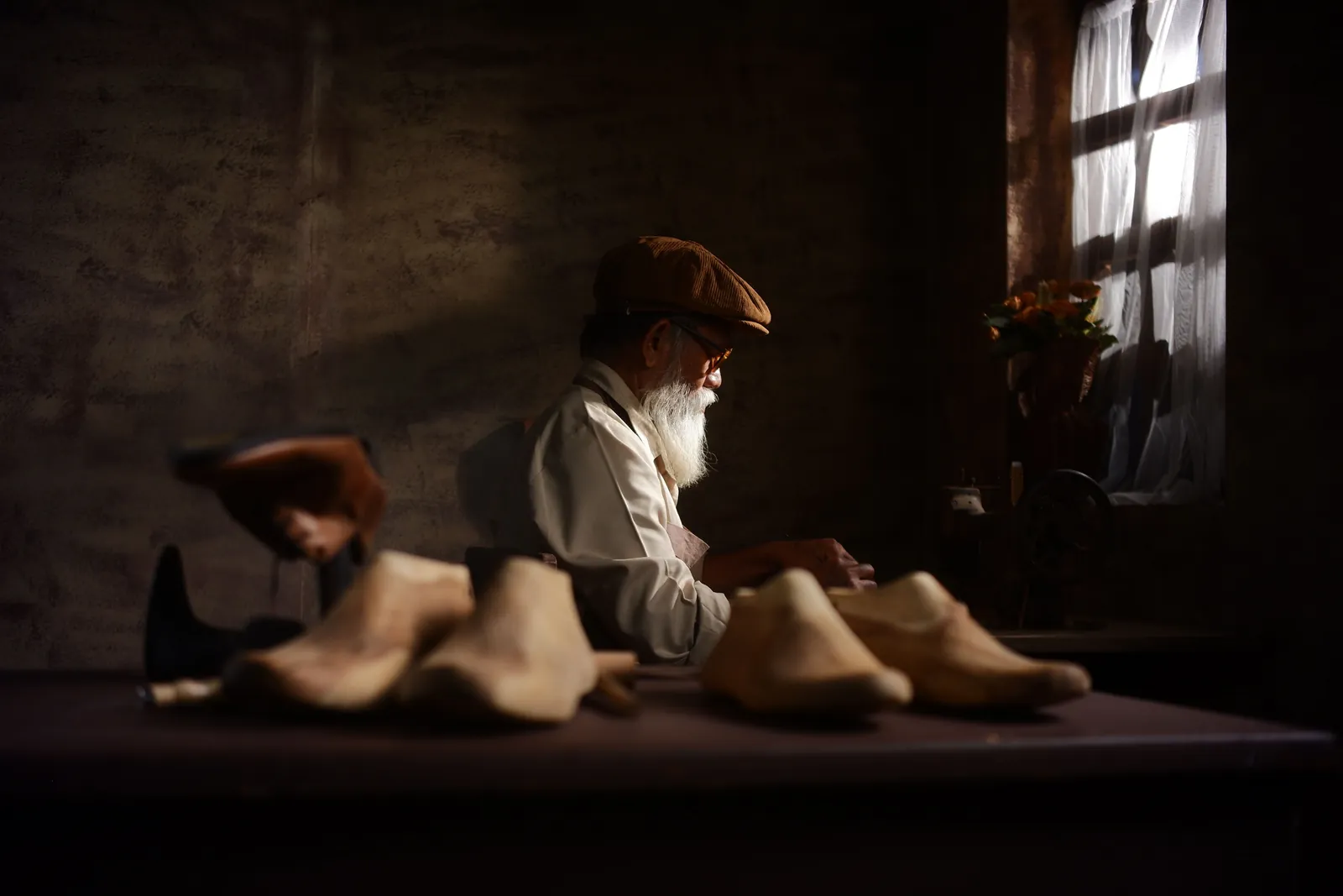 Master craftsman handcrafting bespoke leather shoes in a warm studio workshop
