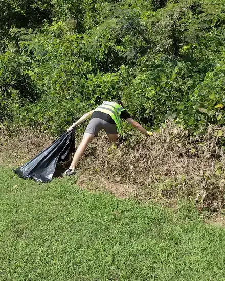 A volunteer clearing litter from roadside brush