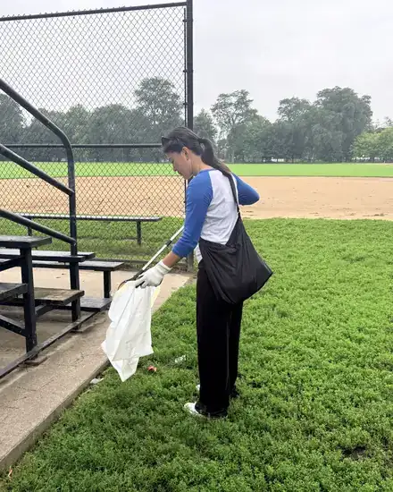 A volunteer clearing litter beside a ball field