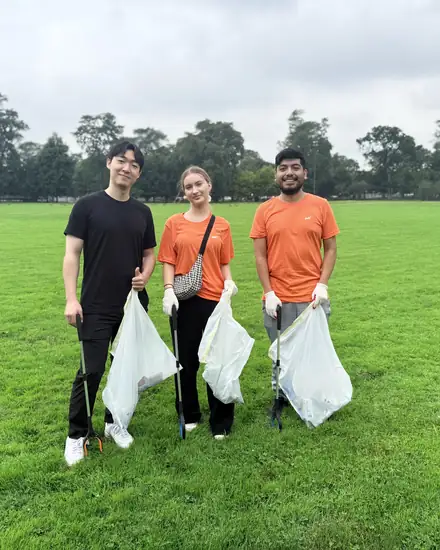 Three volunteers collecting litter in a park