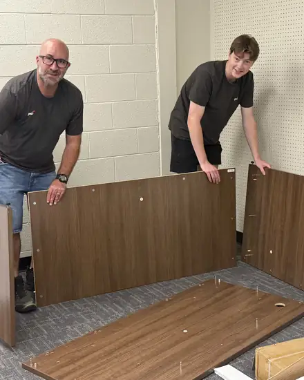 Two volunteers assembling furniture for a classroom