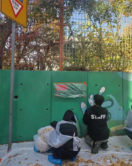 Volunteers painting a flower mural along a wall