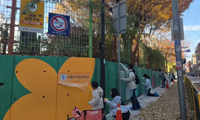 Volunteers painting a long outdoor mural
