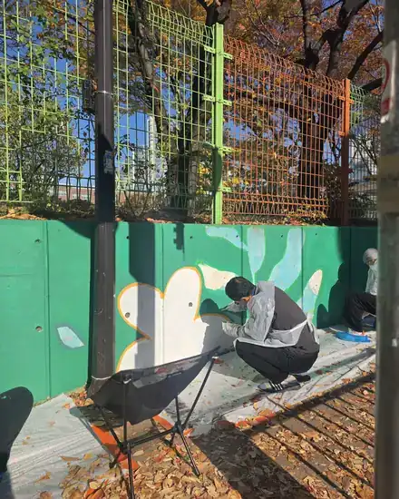 Volunteers painting a mural on a school wall
