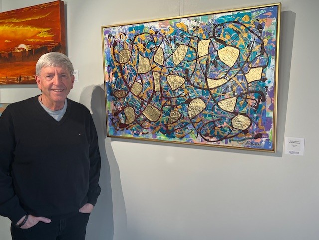 William Rothenbach standing in front of one of his abstract expressionist paintings. 