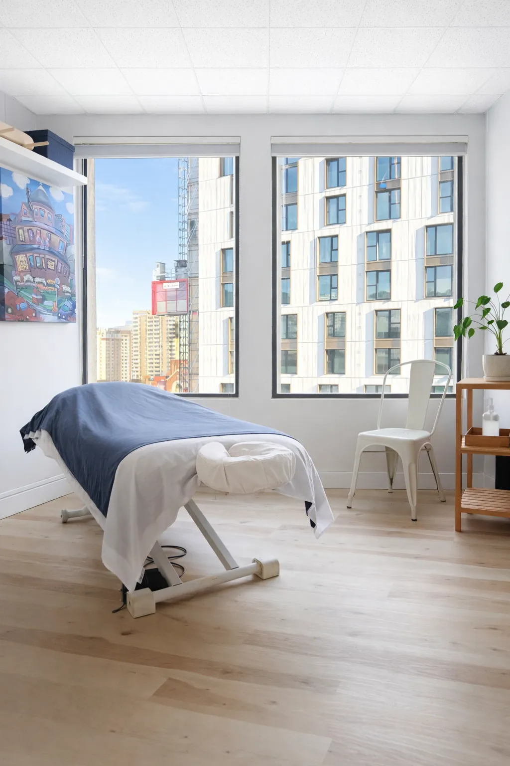 Bright treatment room with a massage table by the window