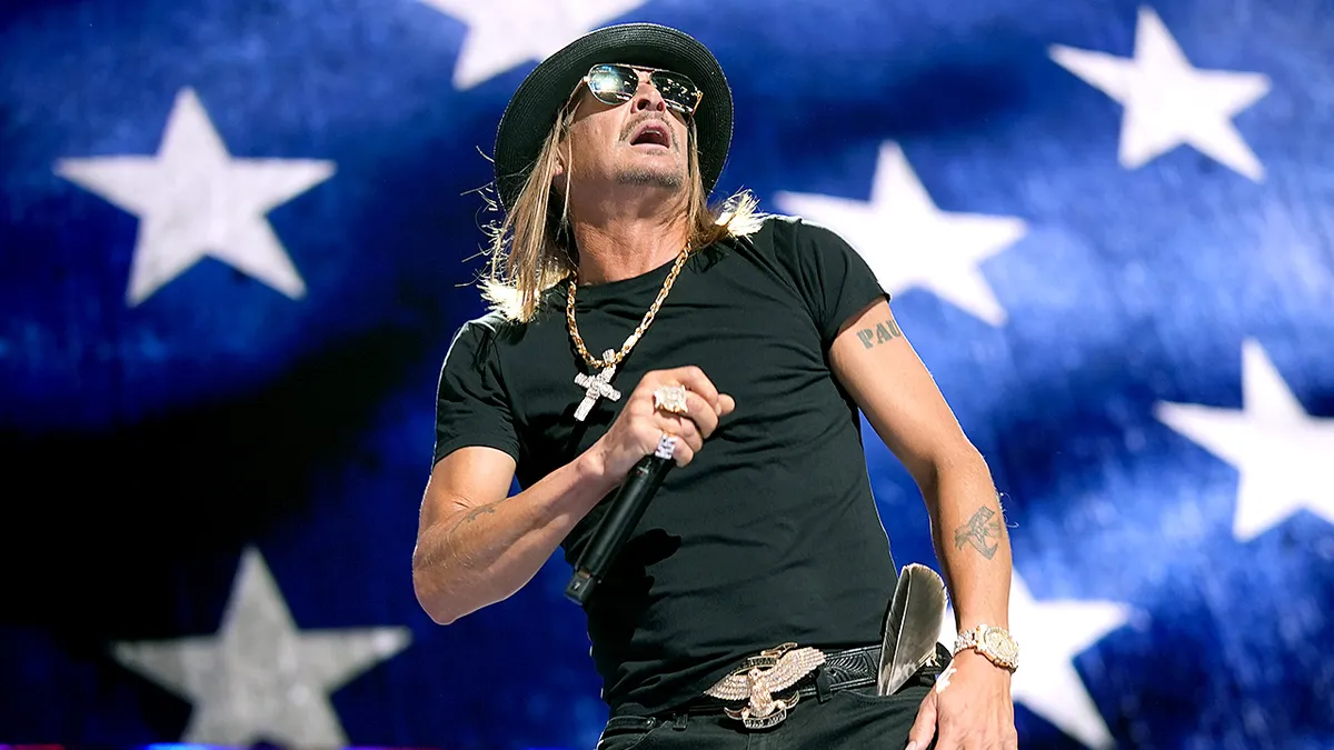 A performer on stage with a microphone, sunglasses, and hat, standing in front of a large American flag backdrop. Ideal for marketing concert or festival ticketing solutions, highlighting MainGate Tickets’ expertise in handling large-scale, high-energy live events with fast check-ins and seamless ticketing.