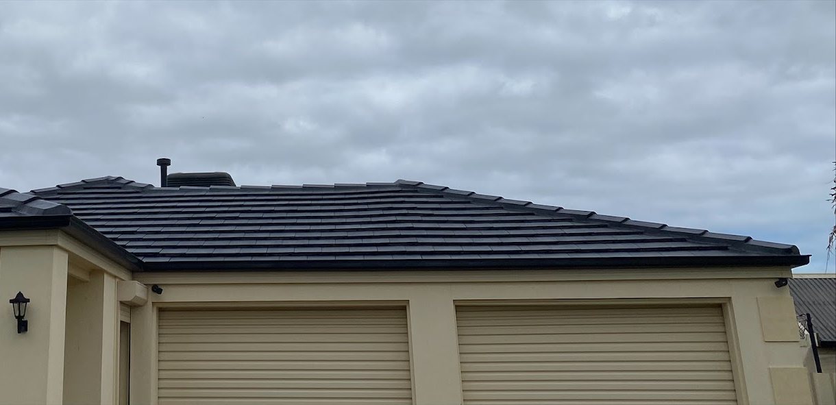 The same Burton home after restoration, with a dark even tile roof.