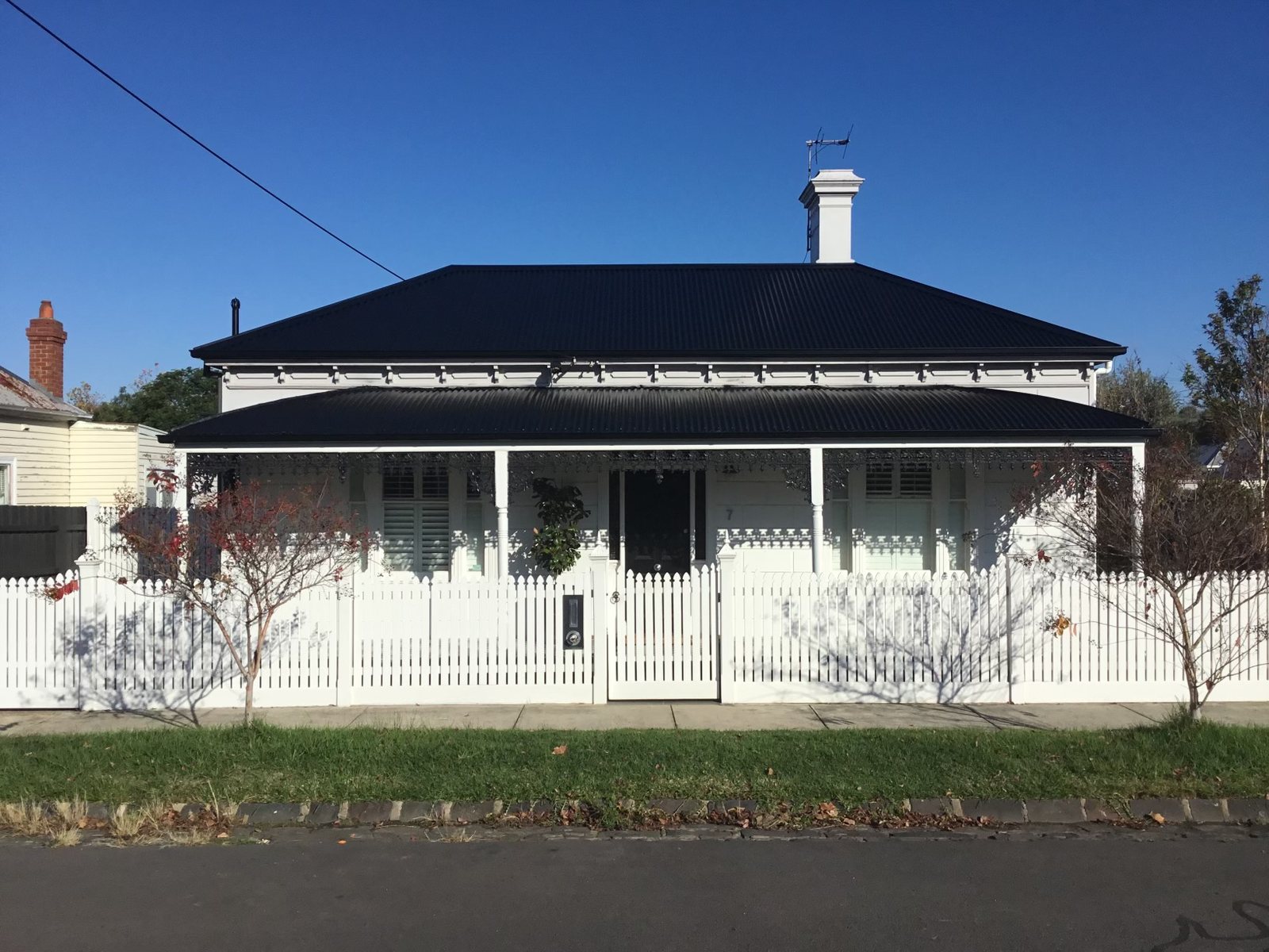 The same white cottage after the iron roof was restored in black
