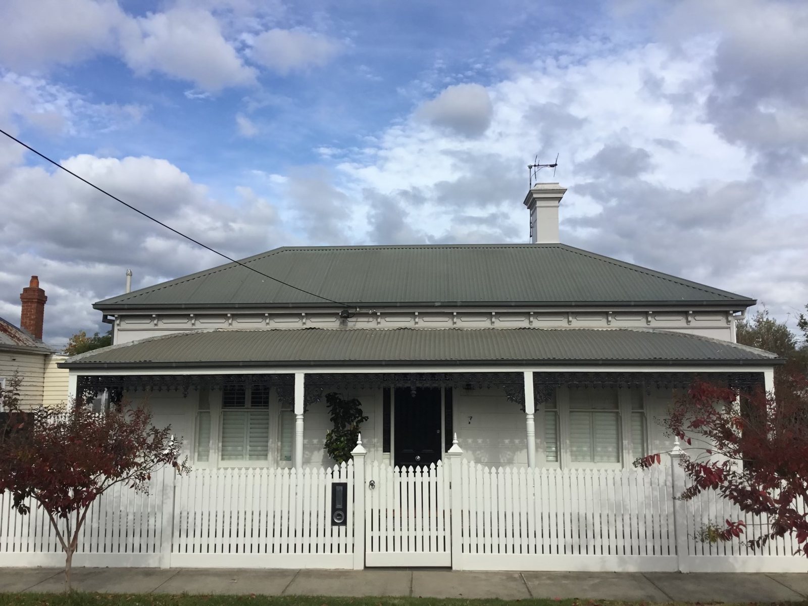 White cottage with a pale, weathered corrugated iron roof