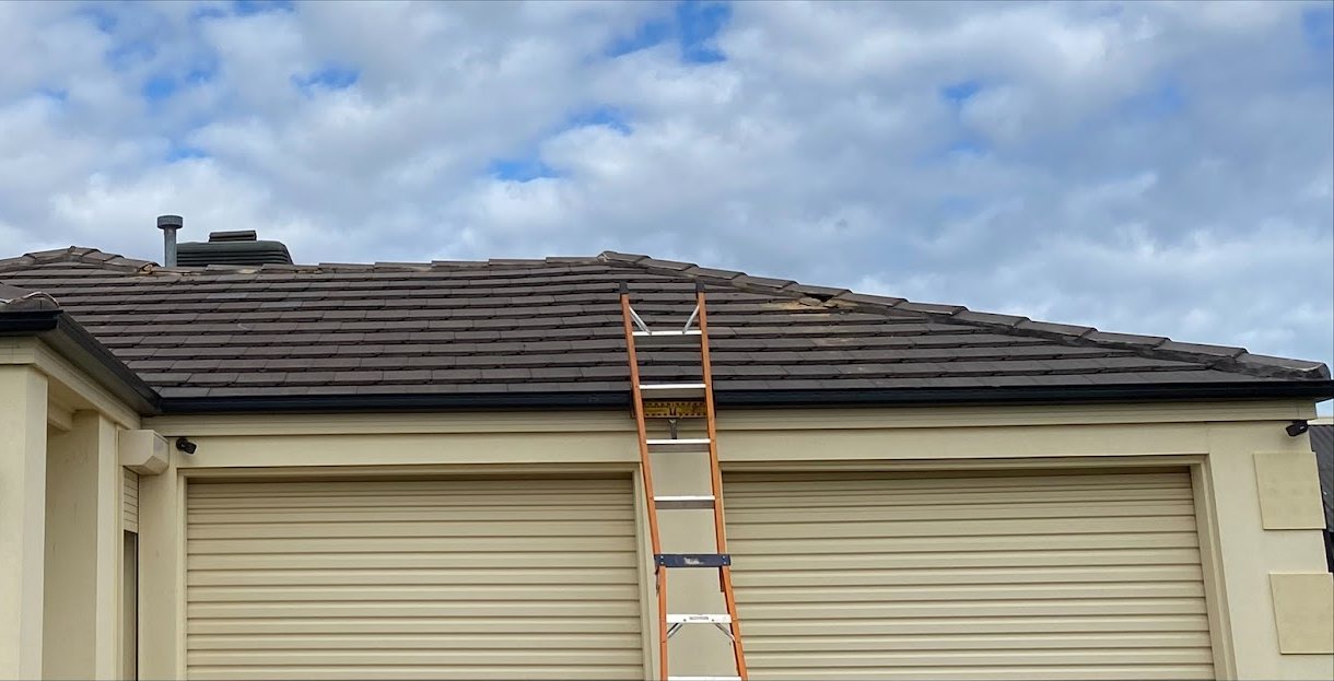 Burton home before roof restoration, faded tiles and a ladder against the gutter.