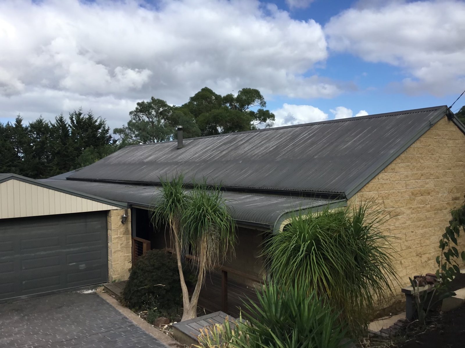 Stone and brick home with a dull, weathered corrugated metal roof