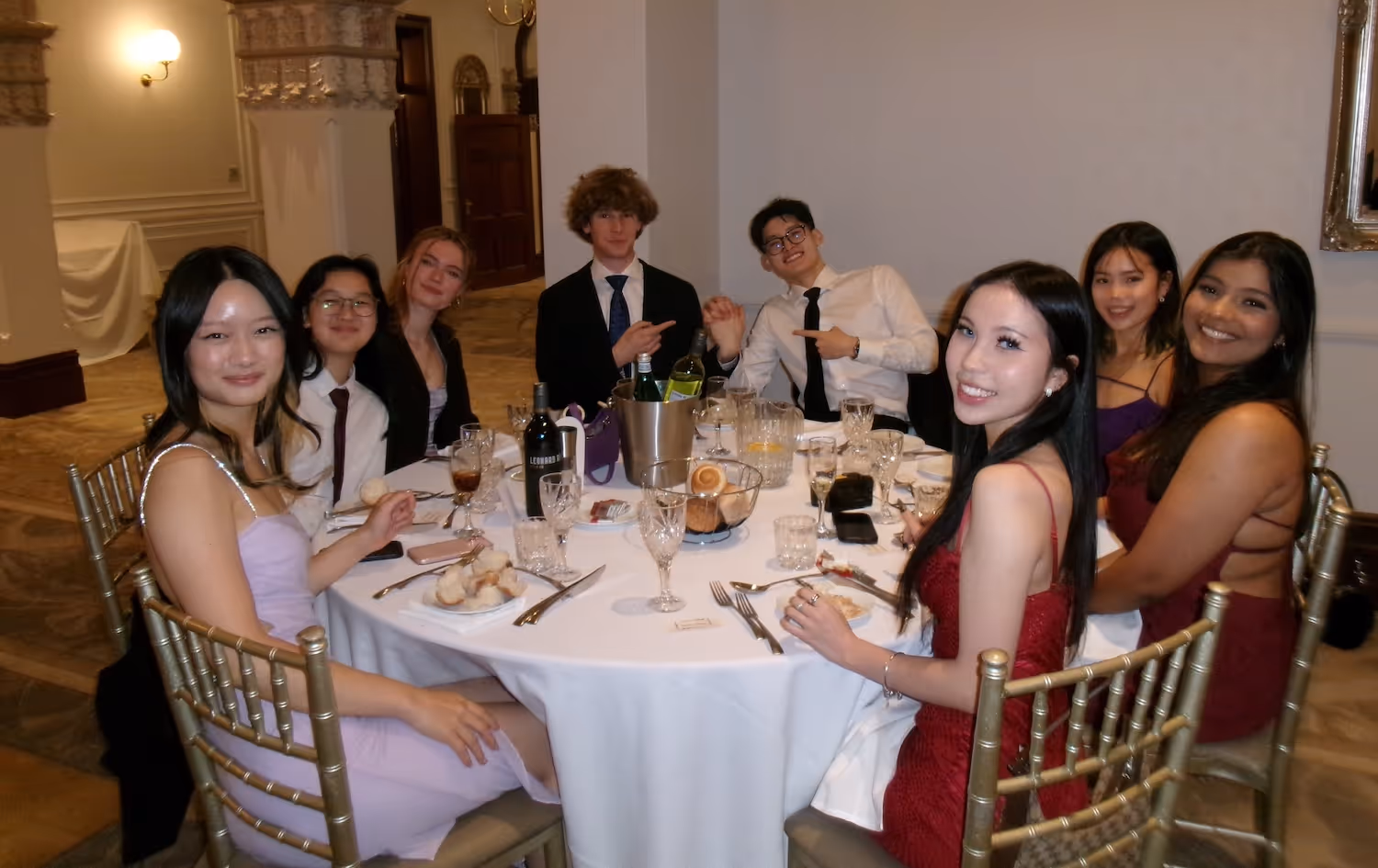 Eight cognito staff dressed formally sitting around a round table with drinks and bread rolls in an elegant room.