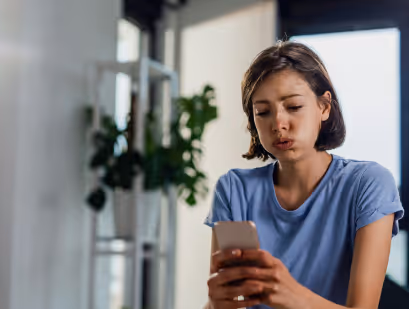 alt="Frau schaut verzweifelt auf ihr Handy"