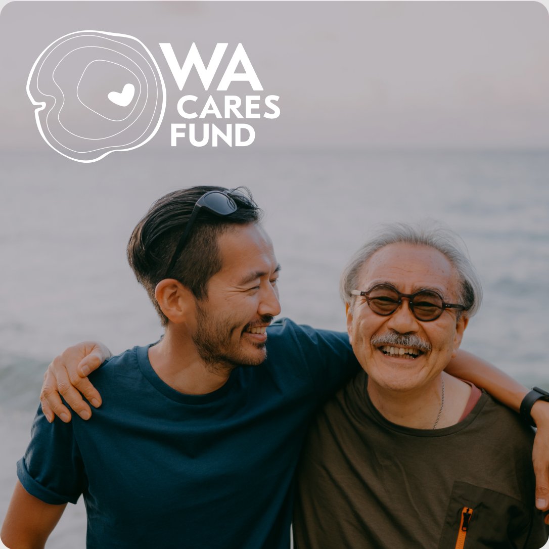An adult son with his arm around his father at the beach, with the WA Cares Fund logo