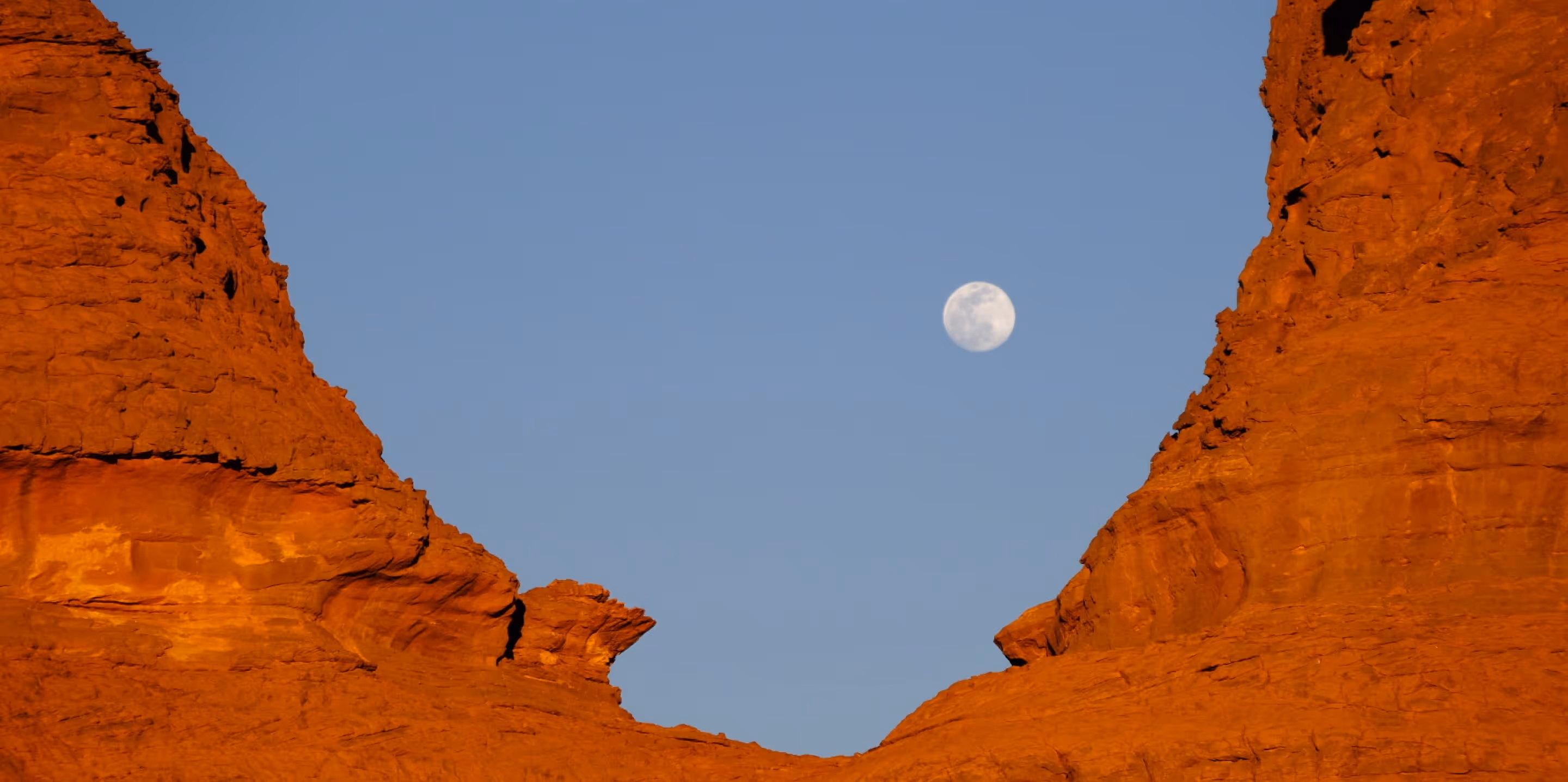 a moon in the sky over a canyon