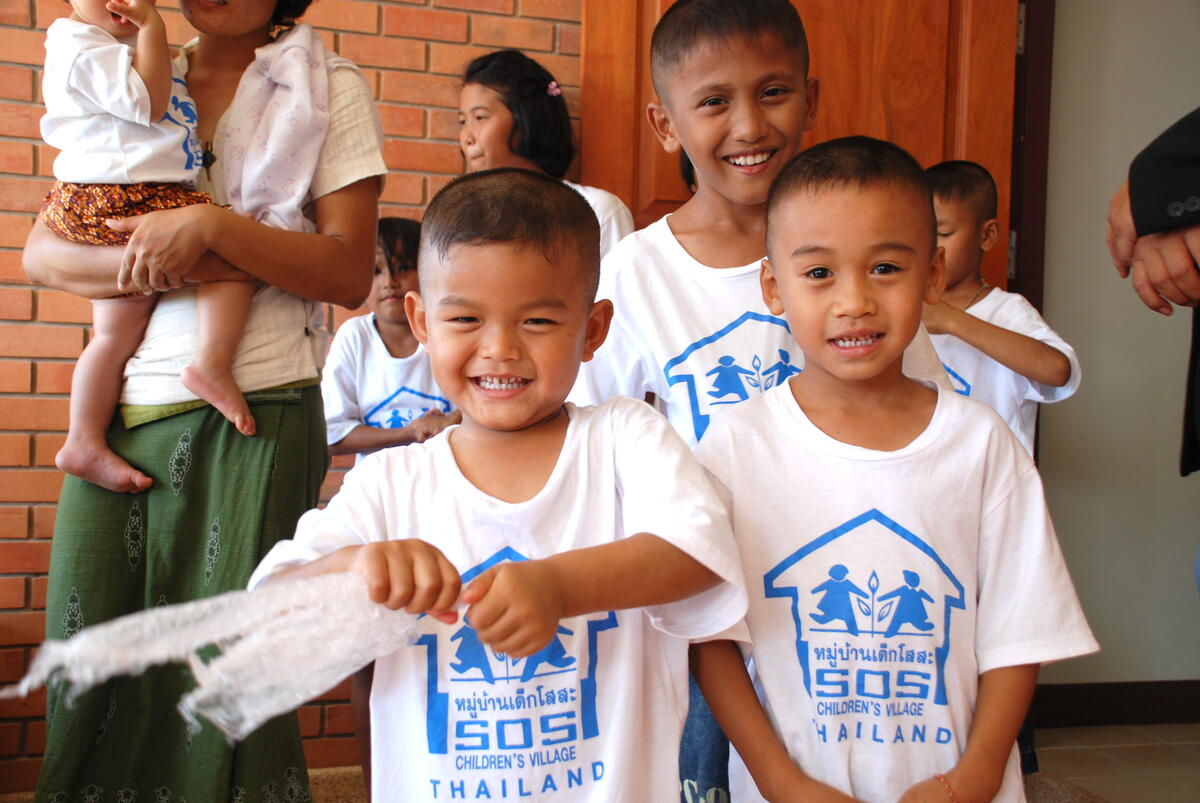 Children smiling outside an SOS Children’s Villages Thailand home, highlighting the nonprofit’s family-based care and education support.
