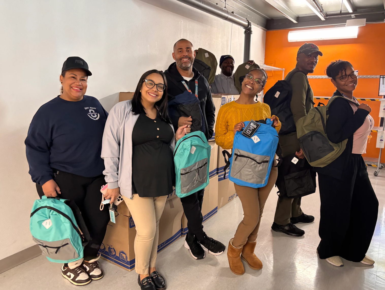 Figma employee volunteers pose for a goodfie with the assembled backpacks with school essentials