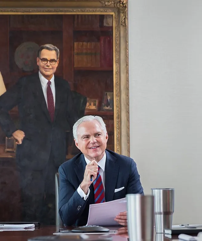 Robert Balentine sitting in front of his father's painting at a company meeting