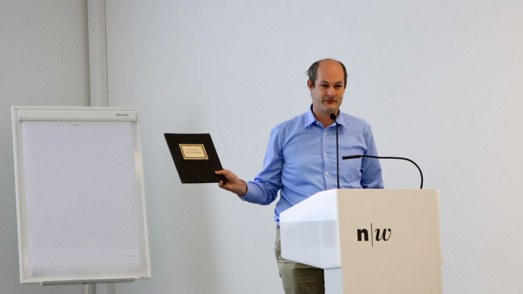 Julien Schumacher hält ein altes Mitgliederregister in den Händen