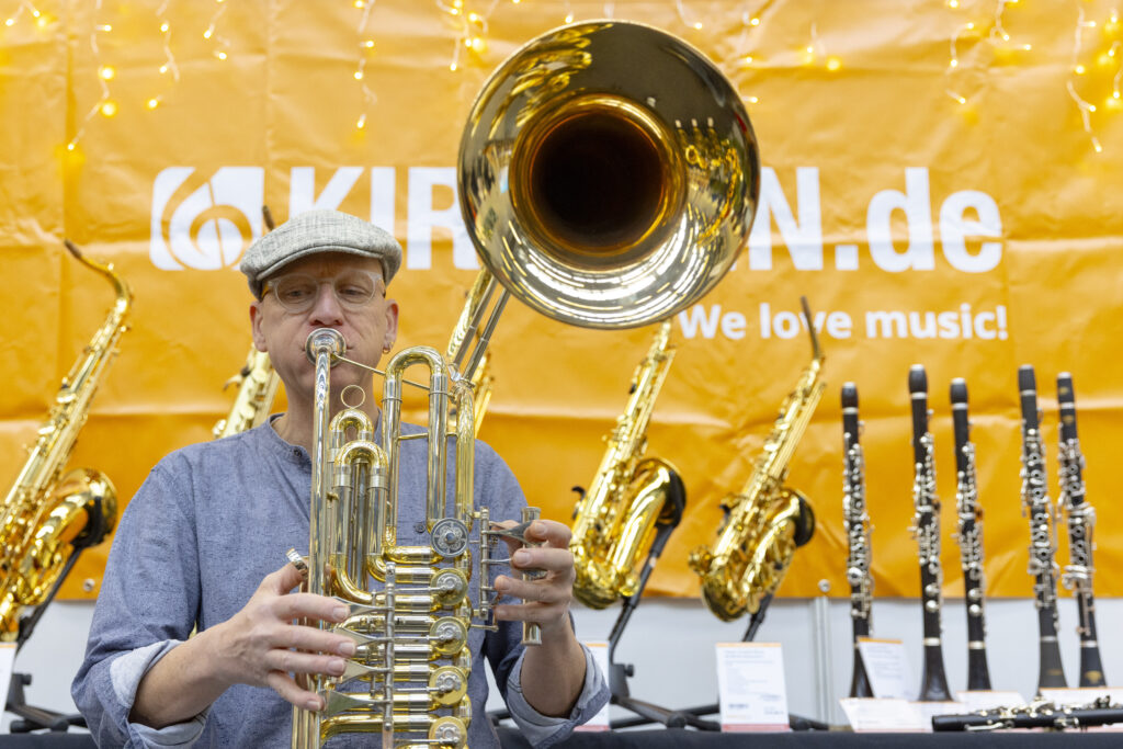 Ein Tuba-Spieler, im Hintergrund verschiedene Holzinstrumente