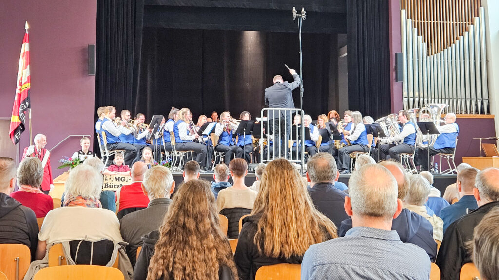 eine Musikgesellschaft auf der Bühne und viel Publikum im Saal
