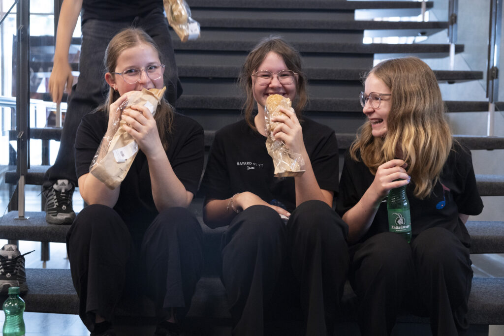 tre ragazze siedono sulle scale e mangiano panini