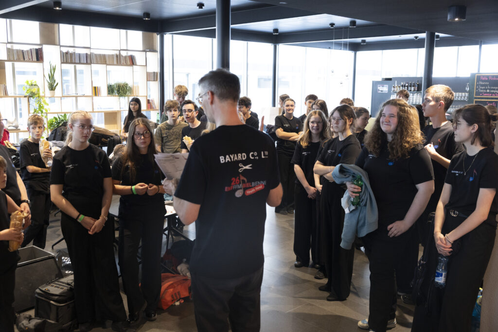 Gregory Heiniger dà istruzioni ai ragazzi della Youth Band, in semicerchio di fronte a lui.
