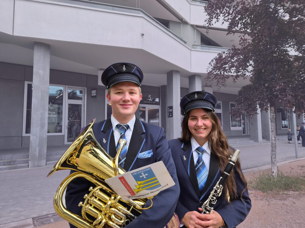 Jonas Heutschi mit Euphonium und Nina Moser mit Klarinette in der Hand, beide in Uniform mit Hut