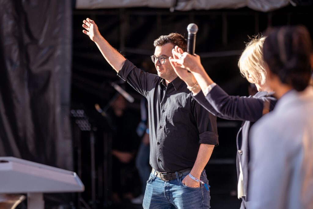 Simon Büchel winkt dankend ins Publikum, daneben applaudiert Nadja Günthör mit Mikrofon in den Händen