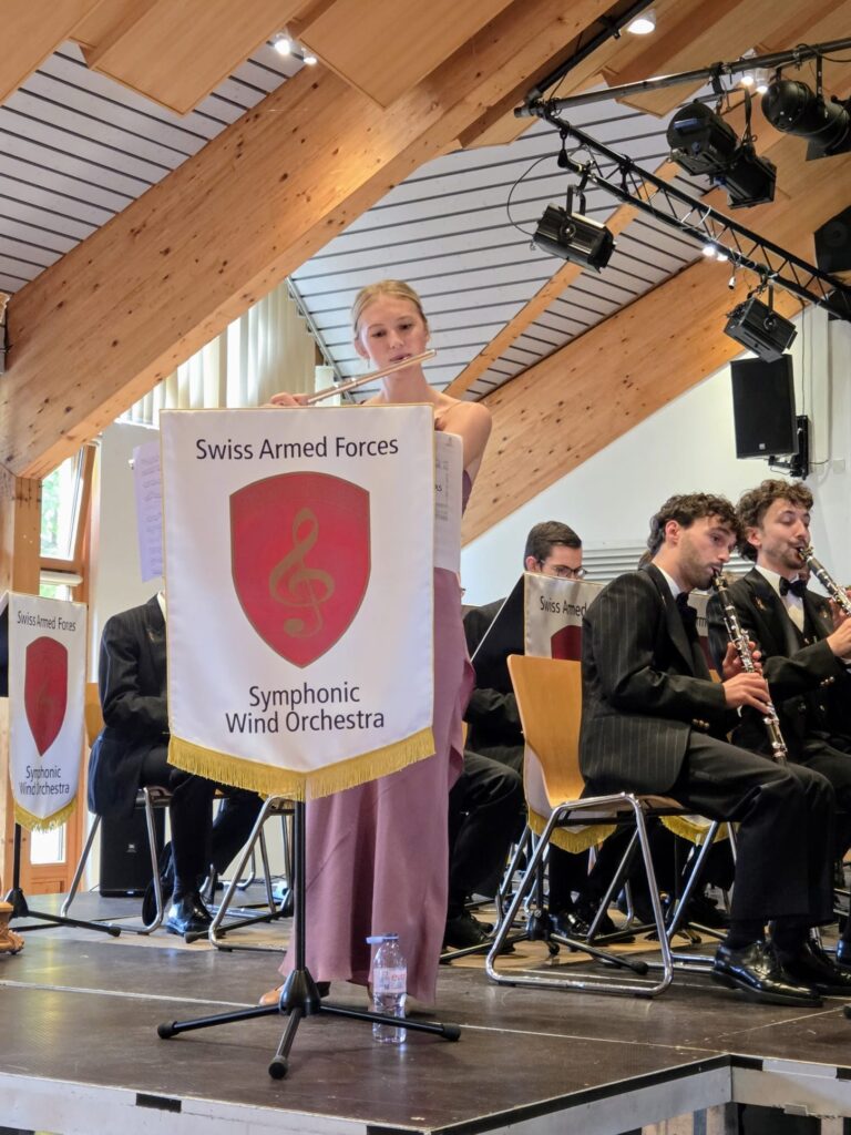 Célestine Crelier à la flûte traversière, accompagnée par l'Orchestre symphonique à vents de la Fanfare d'armée suisse