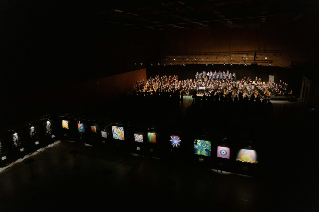 En arrière-plan, l'orchestre, et au premier plan, les peintures des élèves de l'école d'art