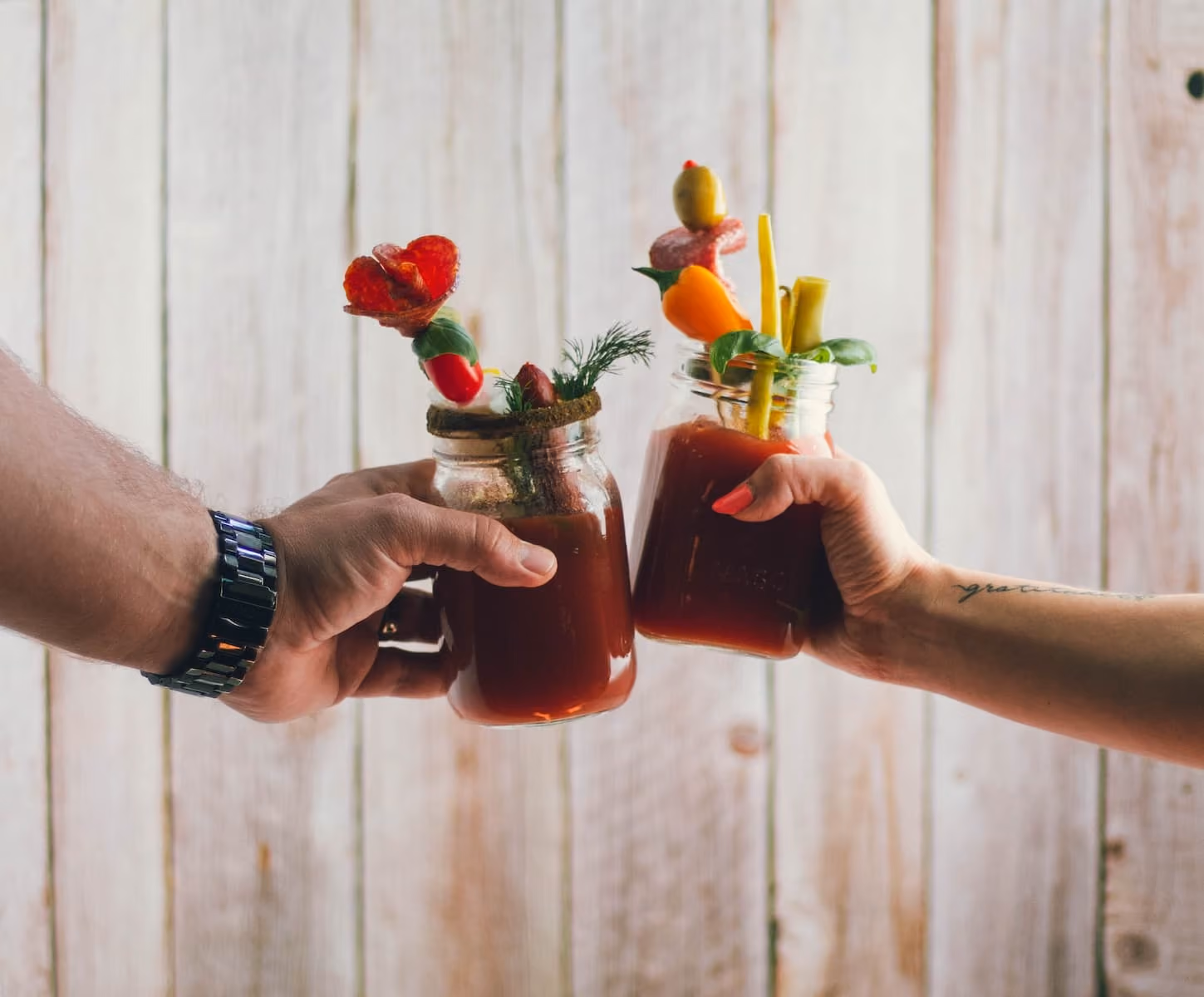 two person holding filled clear glass jars photo