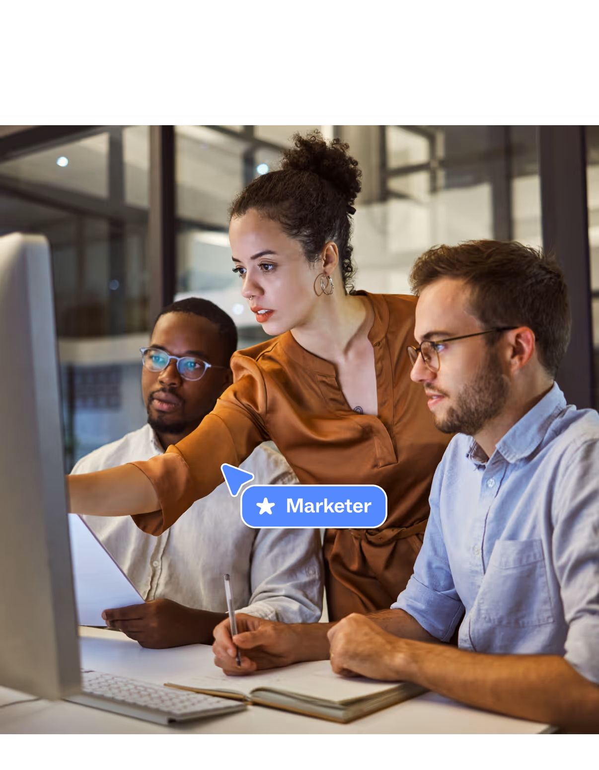 Marketing team working on an omnichannel campaign, reviewing results on a monitor for improved conversion.

