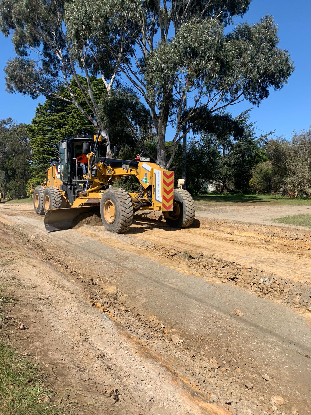 Grader earthmover scraping a dirt road for Linct Group Roads