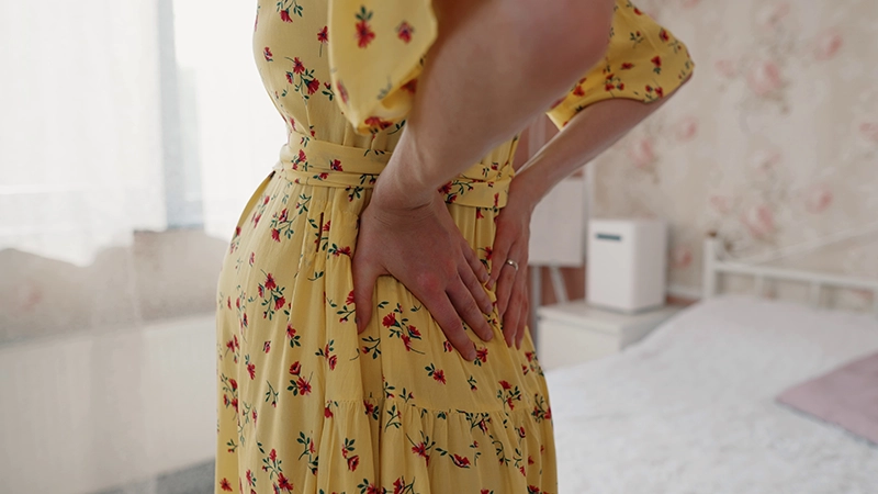 Expecting mother in a nursery holding her back due to pain