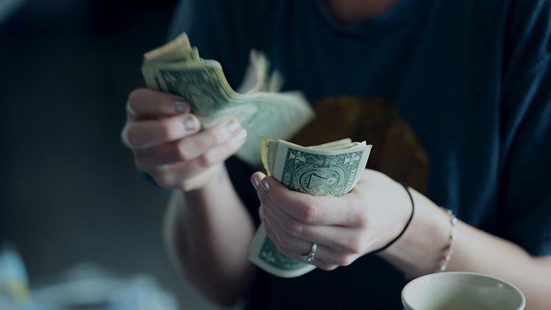 person counting cash with a coffee cup