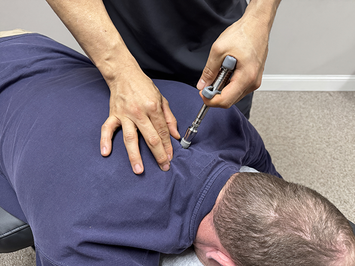 chiropractor dr. victor adjusts a patient's neck using the activator method