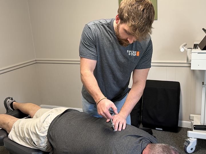 chiropractor dr. derrick witmer adjusts a patient's back using the activator