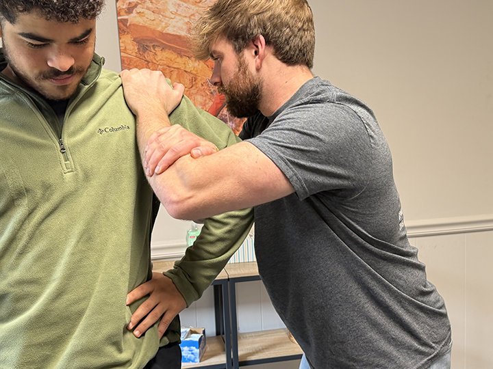 chiropractor dr. derrick witmer adjusts a patient's shoulder