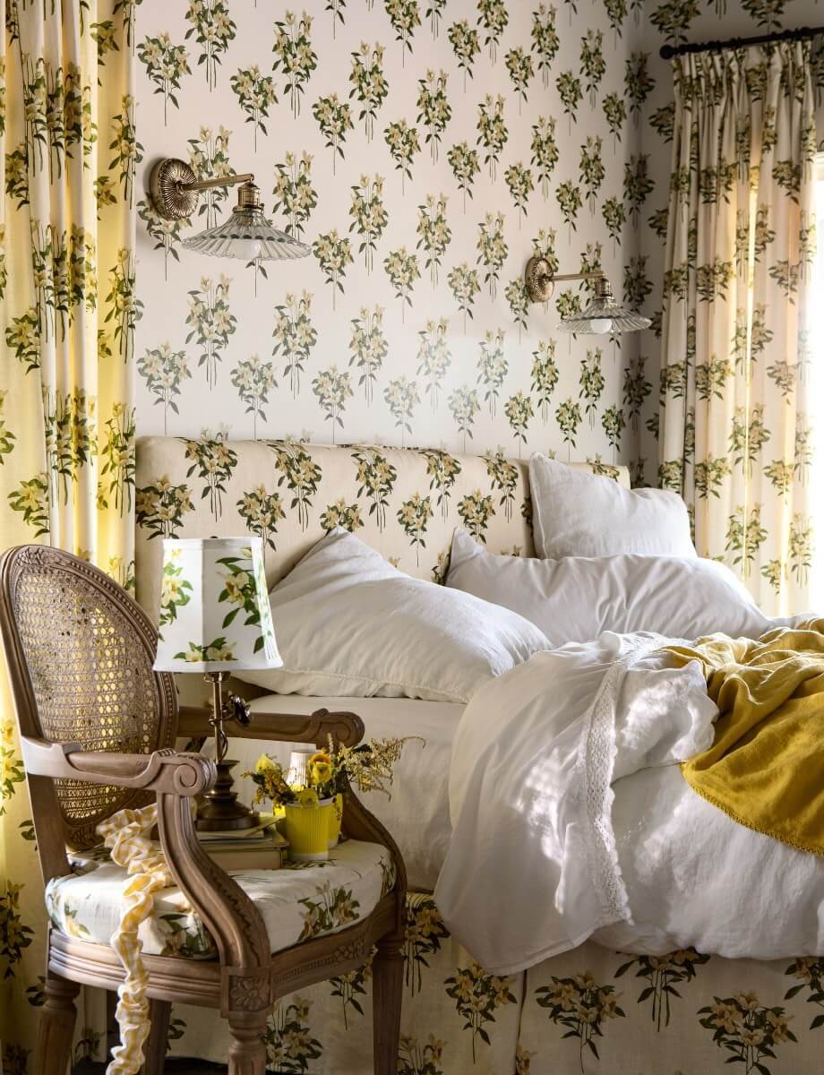 GreenRow Lake House bedroom at Serenbe — floral wallpaper, white linens, wicker chair, and natural-material furnishings from the GreenRow partnership     