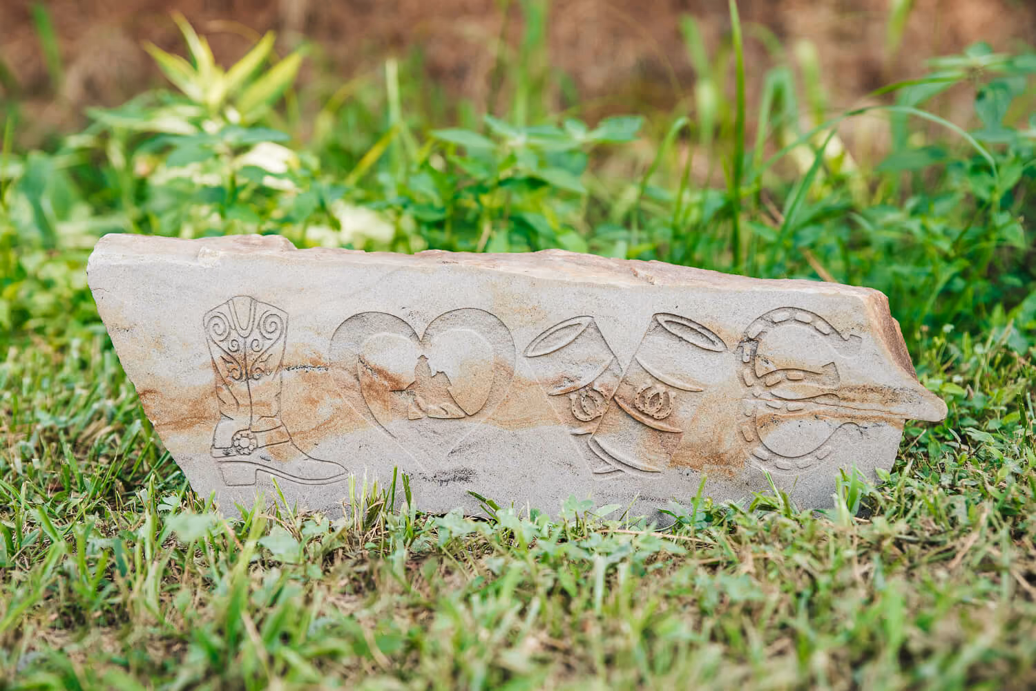 Engraved stone with boots, heart, and container design