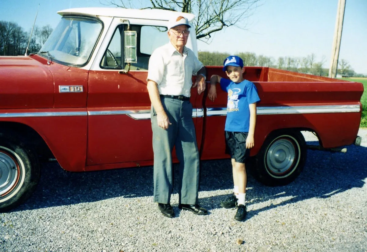 A man standing next to a little boy in front of a red truck.