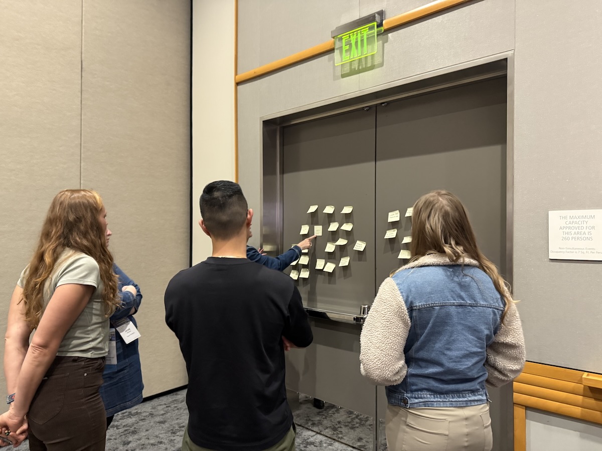 Close-up of workshop participants using sticky notes to cluster and synthesize emerging ideas during an ideation exercise