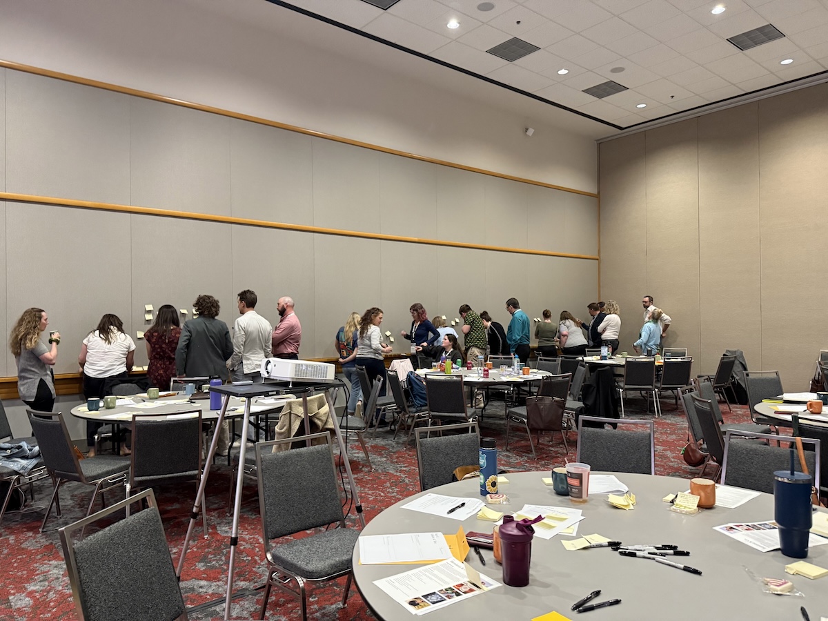Wide-angle view of a collaborative workshop applying structured brainstorming techniques in a conference setting