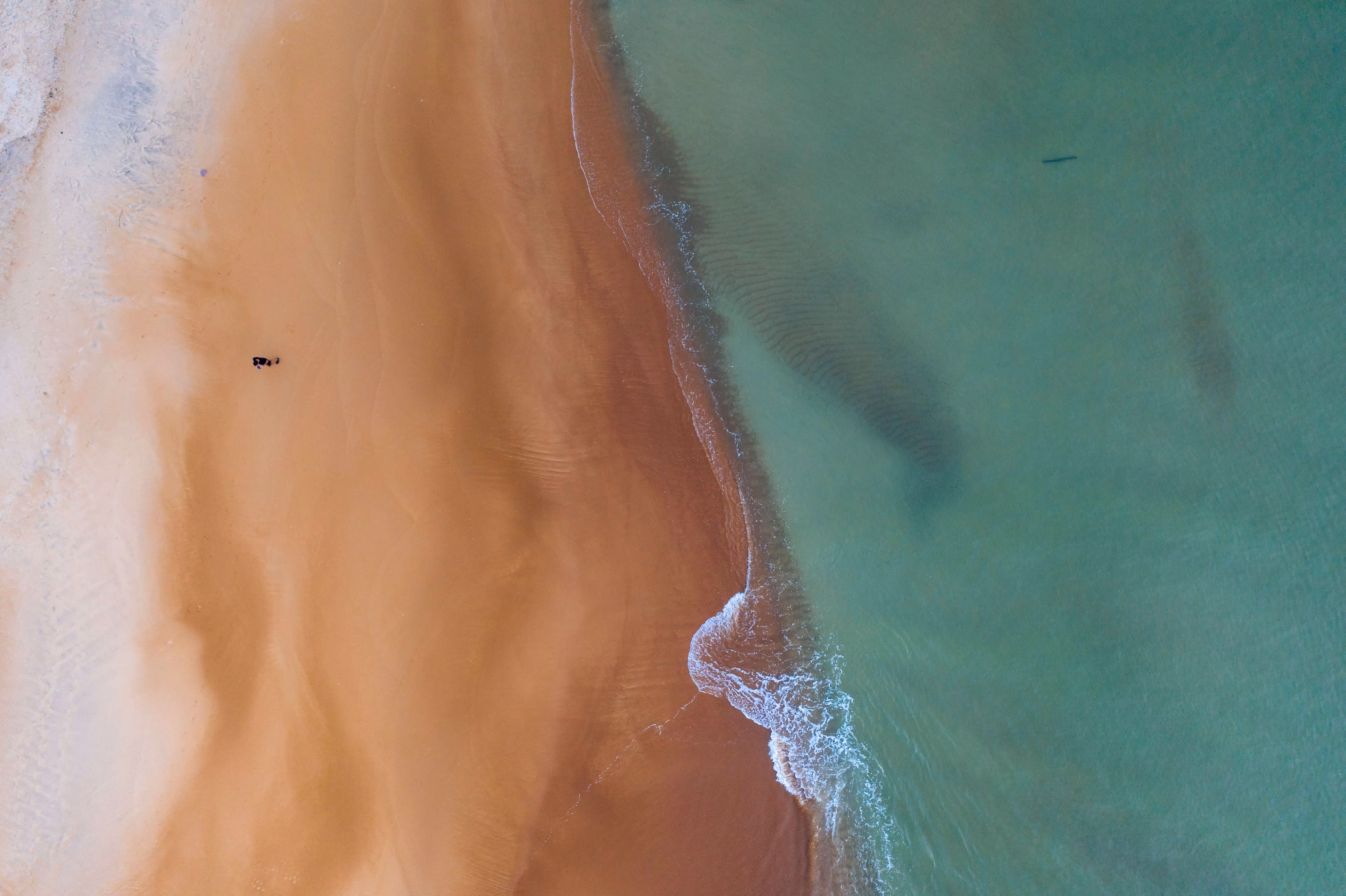 Drone photo of seawater and a sandy beach